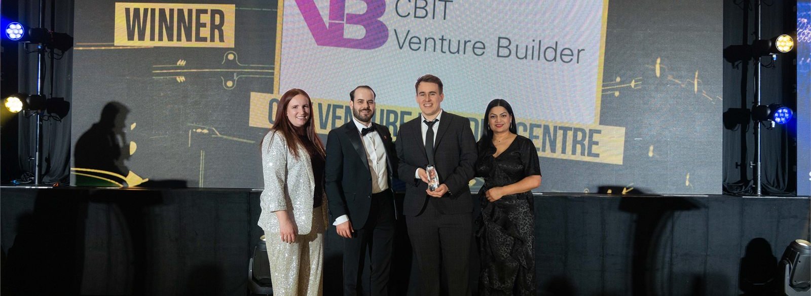 The CBIT Venture Builder team on stage with the Technology Innovation Champion of the Year trophy and the winner announcement on screen
